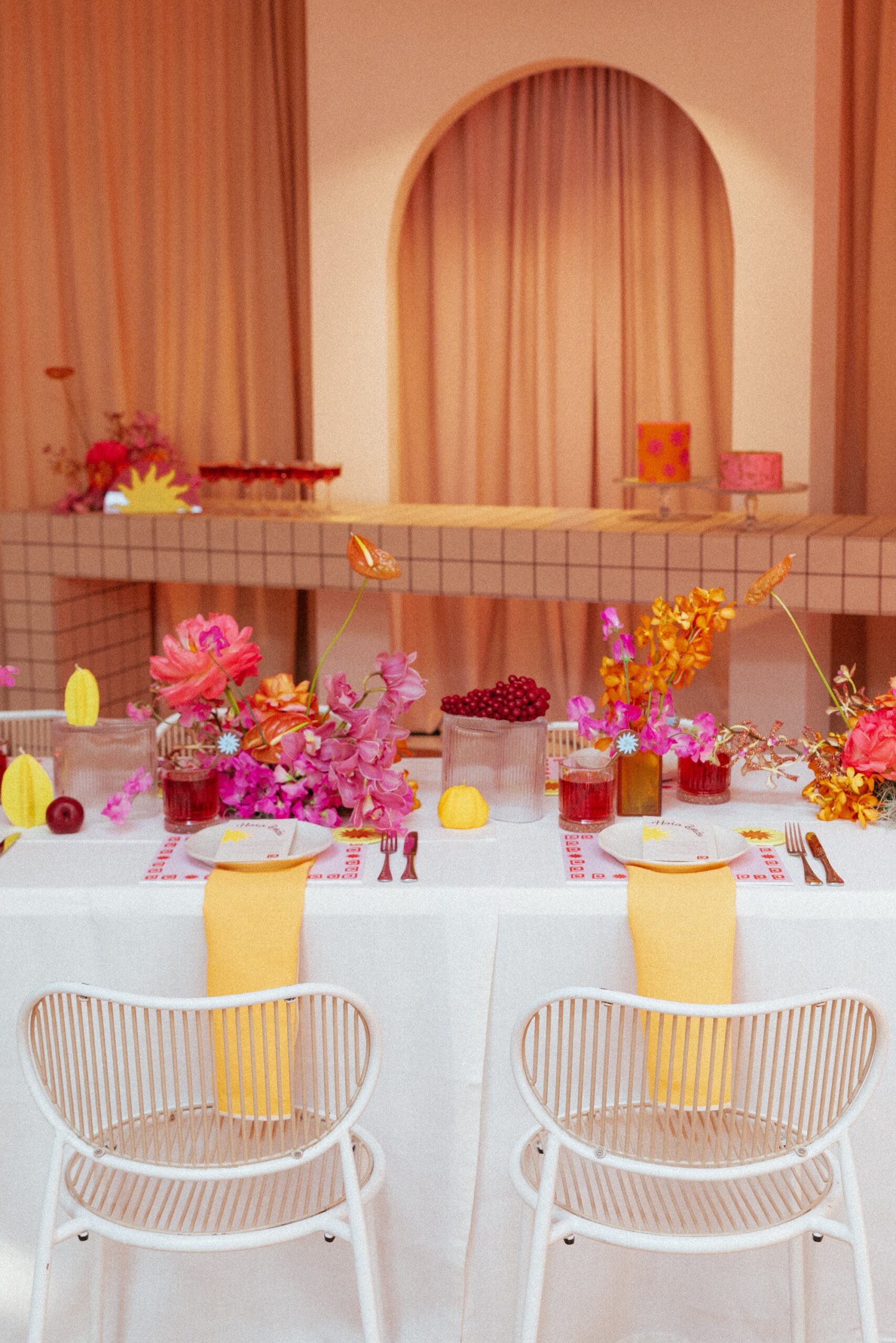 A bright and fun table setting at an event in Melbourne. The table is laid with fruit themed candles, orange napkins and bright florals. A perfect set up for a bridal shower. 
