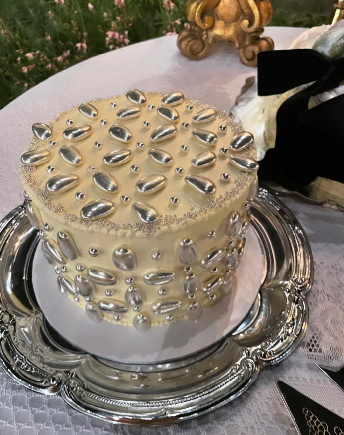 Cream coloured buttercream wedding cake covered in silver chrome edible beads, sitting on a silver vintage plate.